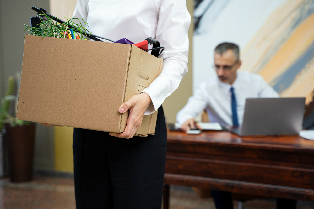 mujer despedida de su trabajo llevando sus pertencias en una caja